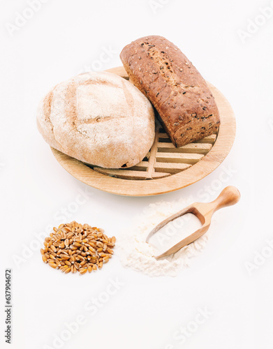 immagine primo piano di pagnotte artigianali da farine di origine biologica, tagliere, misura di farina e chicchi di grano duro, sfondo bianco photo