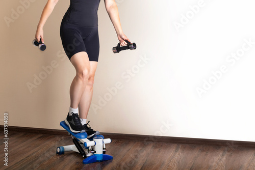 Home fitness. A woman training on a stepper at home.