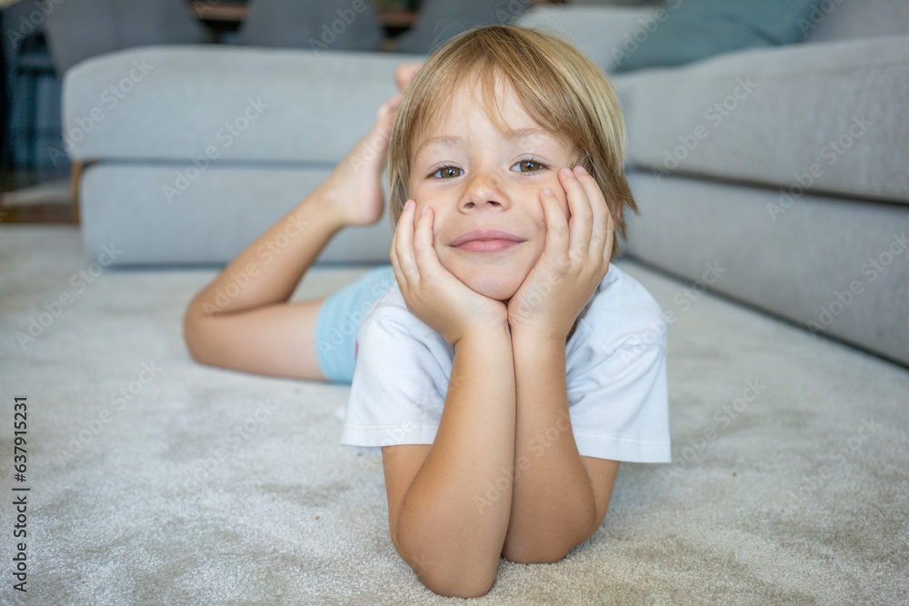 portrait of a little boy smiling lying on a carpet at home portrait of a little boy smiling lying on a carpet at home