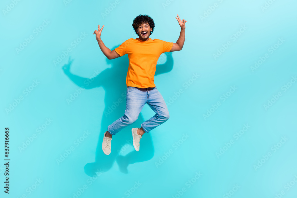 Full body portrait of handsome excited person jumping demonstrate v-sign empty space isolated on turquoise color background Full body portrait of handsome excited person jumping demonstrate v-sign empty space isolated on turquoise color background