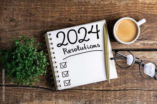 New year resolutions 2024 on desk. 2024 resolutions list with notebook, coffee cup on table. Goals, resolutions, plan, action, checklist concept. New Year 2024 template, copy space photo