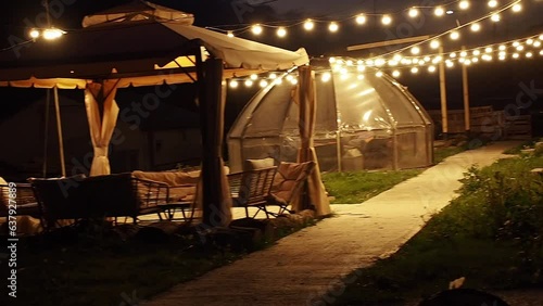 A mountain hotel courtyard with night lights and gazebos on a cozy late evening