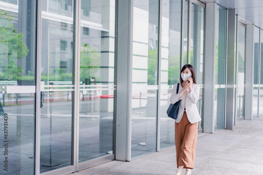 Obraz premium マスクをしてスマホを使う若い女性