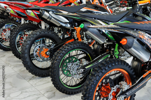 There are many colorful motorcycles for sale in the exhibition hall. Wheels close-up.