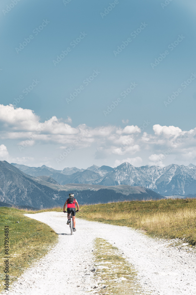 A loner riding a bicycle on a mountain dirt road