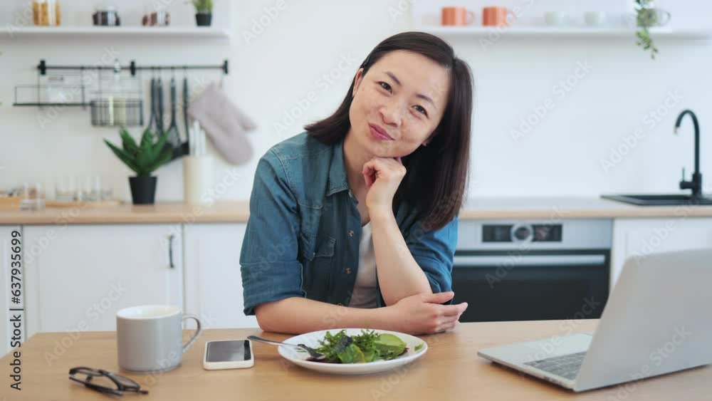 Remote employee sitting at table with laptop and salad Remote employee sitting at table with laptop and salad