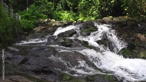 Mountain river flows rushing down the rocks skirting the trees in slow motion