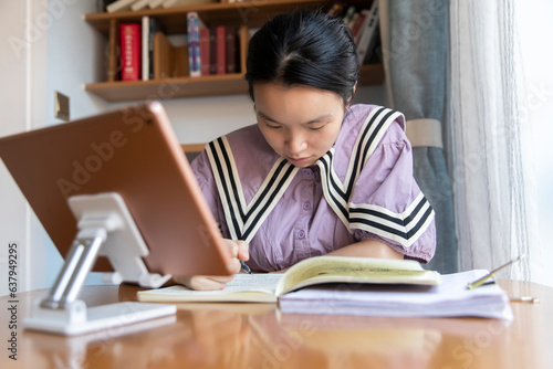 A young Chinese woman is learning on a tablet at home