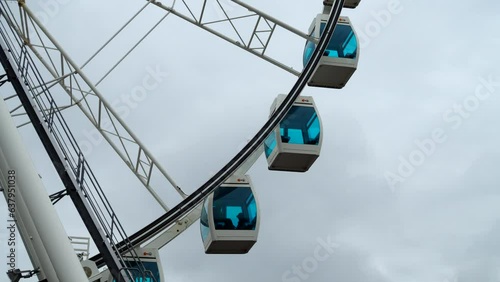 The ferris wheel cabins slowly arriving to the passenger base.