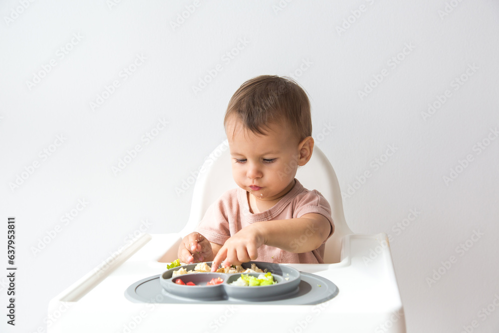 Cute little baby infant eating complementary foods on white background. space for text Cute little baby infant eating complementary foods on white background. space for text