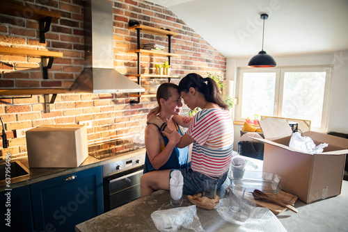 Young female lesbian couple hugging after moving in their new home apartment photo