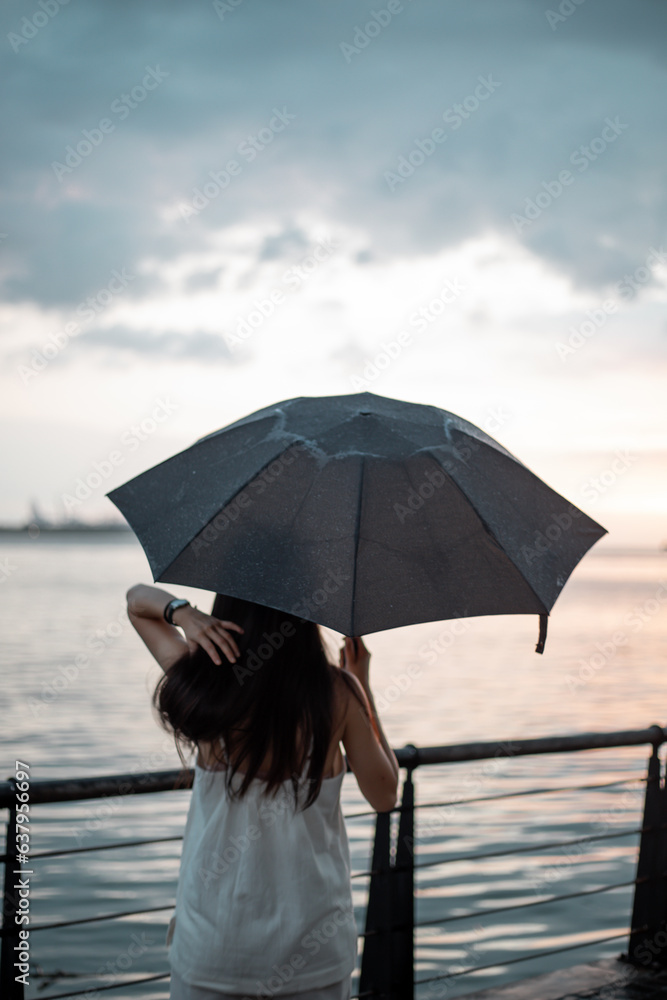 Silhouette  woman holding umbrella in the rain at sea