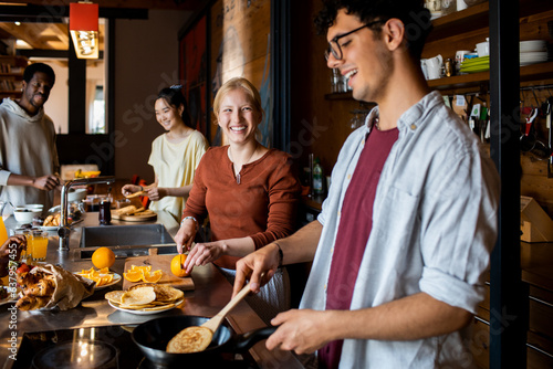 Diverse group of young roommates preparing and having breakfast together in their flatshare apartment photo