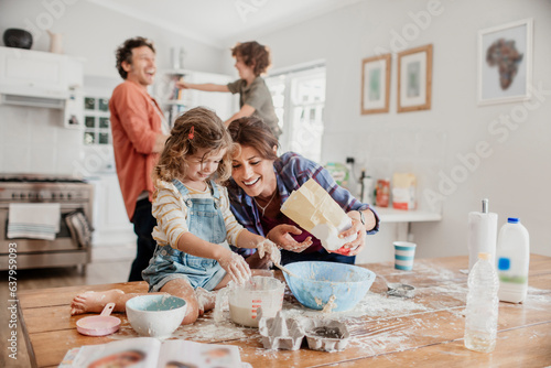Young caucasian family being messy and having fun baking together in the kitchen photo