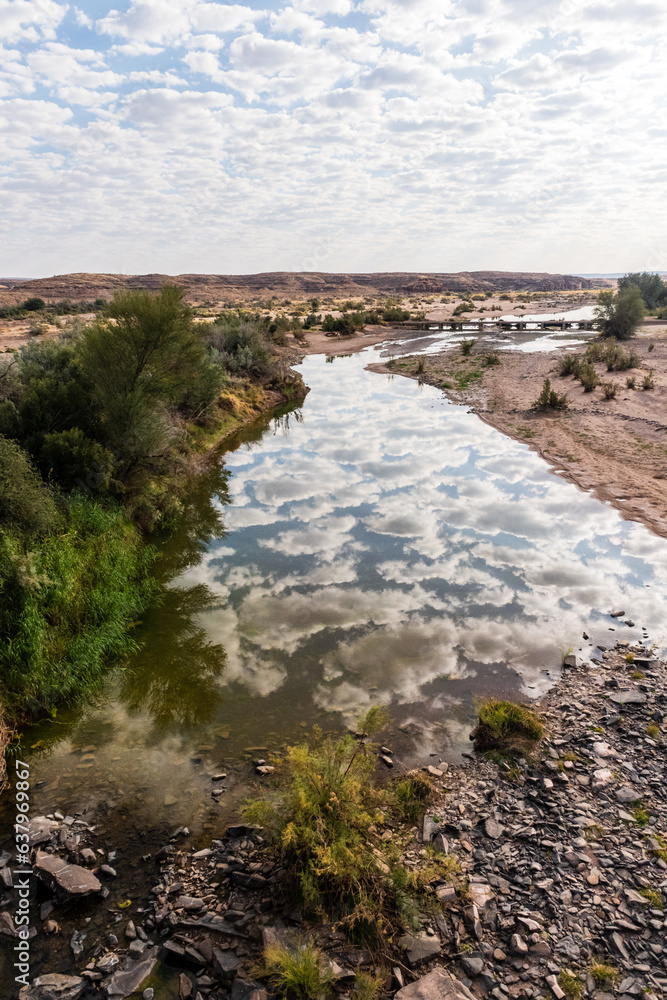 Low scattered clouds are reflected in the Fish River in Southern Namibia