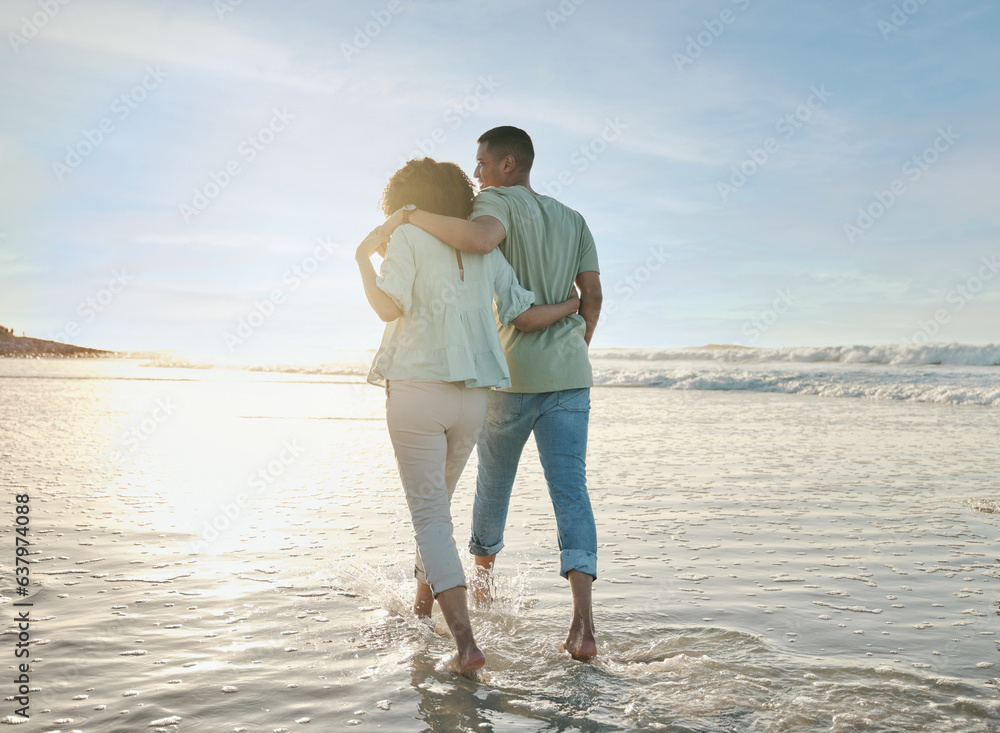 Love, hug and back of couple at the beach walking, bond and relax in nature on blue sky background. Ocean, love and rear view of man embrace woman at sea for travel, freedom and romantic walk in Bali