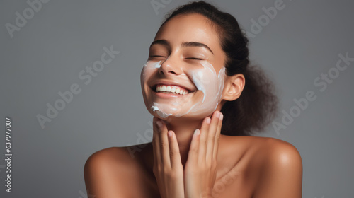 Close up beauty portrait of a laughing beautiful woman applying face cream