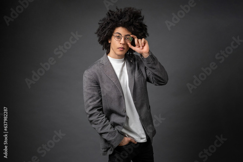 Good-looking youg businessman in eyeglasses on grey background