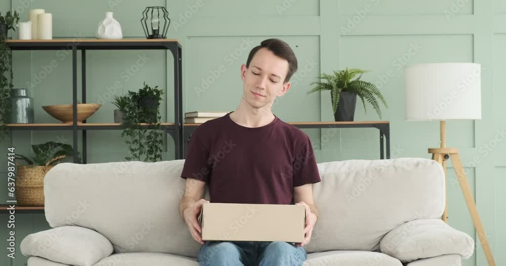 In this carefree moment, a Caucasian man is shown receiving a package and rejoicing over its contents. His face lights up with a joyful smile, reflecting his excitement and happiness. In this carefree moment, a Caucasian man is shown receiving a package and rejoicing over its contents. His face lights up with a joyful smile, reflecting his excitement and happiness.