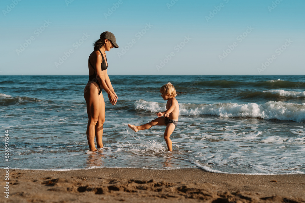 beautiful sports mom runs with her son along the seashore on the beach