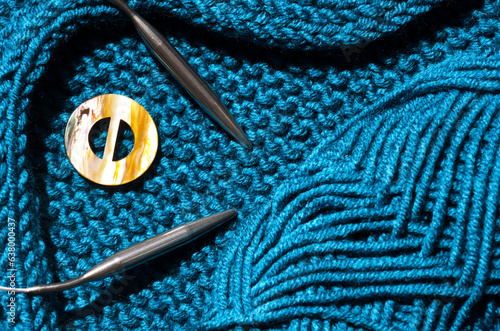 Turquoise textured jersey is knitted on knitting needles from semi-woolen yarn.