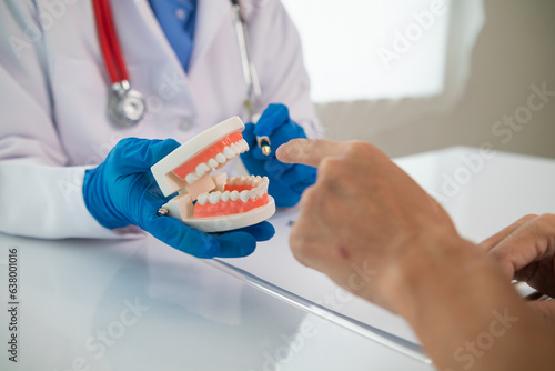 Dentists recommend ways treat problem teeth and dentists also advise patients know take care of their teeth after treatment is completed. Dentist holding dentures in hand and talking to patient