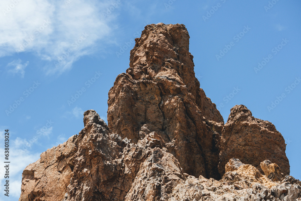 Very rocky volcanic formations with green vegetation around on island  