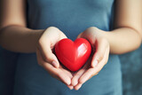 Close up of happy charity volunteer young woman hands holding red heart wishing hope or gratitude for World Hearts Day. Compliment day concept suitable for prayer and trust.