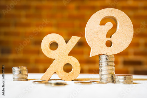 Percentage and question mark with coin on wood table, raising or lowering Fed interest rates to correct inflation concepts.