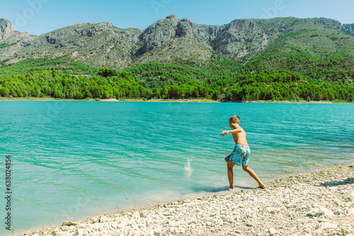A teenager in shorts walks near a mountain lake against the backdrop of a beautiful landscape beautiful mountain landscape with a child against the backdrop of mountains and a lake. High quality photo