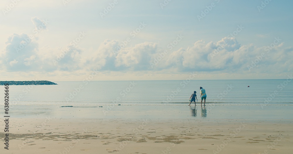 happy Asian family mother and son walking playing together enjoy fun on tropical sea beach against blue sky waves on background in summertime, lifestyle leisure holiday vacation travel concept