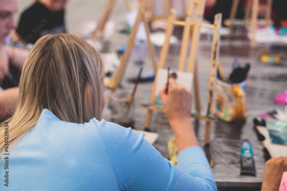 Obraz premium Process of drawing, group class of talented students with painting easels and canvases during lesson of watercolour painting outdoors, drawing class for adult artists in art school