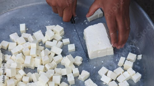 4k footage of an Indian male slicing white cheese/paneer using a knife on the utensil - on occasion of village marriage photo