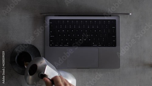 Businessman typing on a computer keyboard and pouring coffee
