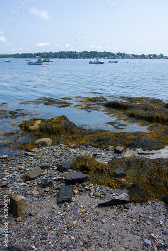 View of the beach and sailboats docked in the bay in Harpswell, Maine. Picture taken during the summer on a partly cloudy day. photo