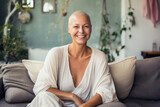 Portrait of a strong, beautiful smiling woman with no hair, cancer survivor, sitting on the sofa in her home.