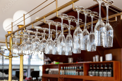 Clean wine glasses hanging upside down above a bar rack in restaurant