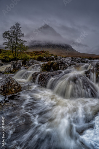 Glencoe, Scotland in the Scottish highlands. Waterfall on a stormy and cloudy day. Scottish weather, mountains, waterfalls and clouds. 