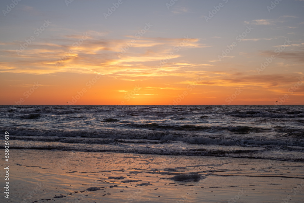 Sunset on the sea and white waves. Scenic view of beach in evening