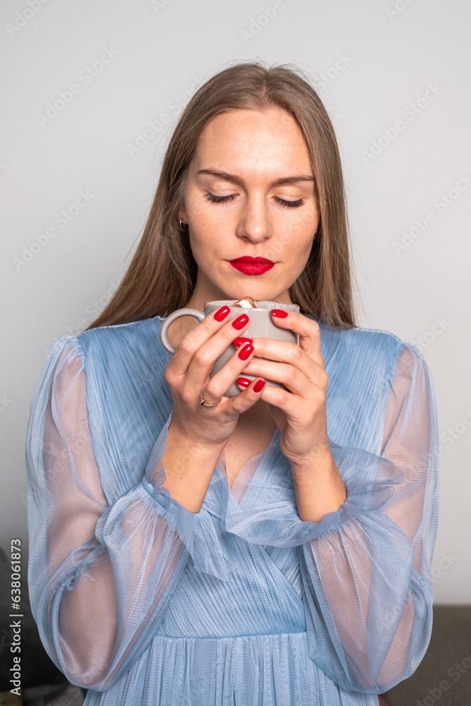 Blurred young serious woman in a light blue dress, looking into a cup of coffee. Blurred young serious woman in a light blue dress, looking into a cup of coffee.