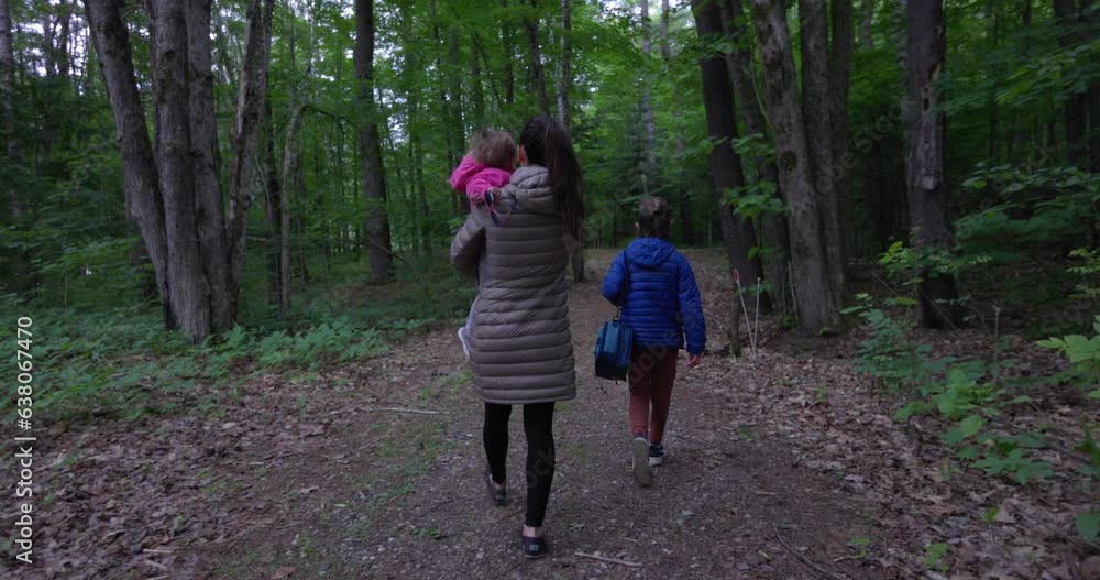 Mother and young kids walking to camp grounds in middle of woods - summer vacation Mother and young kids walking to camp grounds in middle of woods - summer vacation