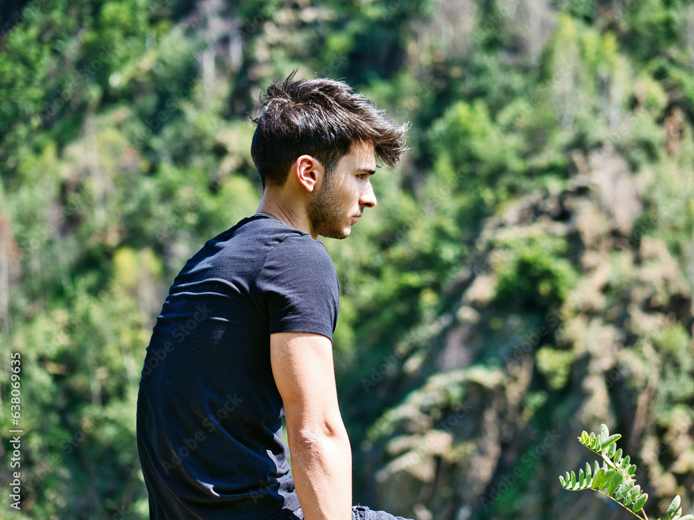 Photo of a man sitting on a rock, contemplating the view Photo of a man sitting on a rock, contemplating the view