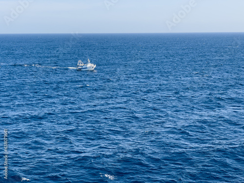 Small, fishing boat at open sea with waves. © PepeSun