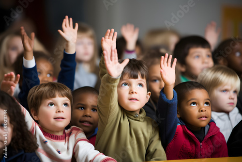 Group of children with hands raised eagerly answering a question in class.  photo