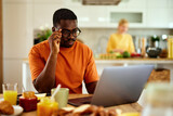 Pensive black man working on laptop during breakfast at home
