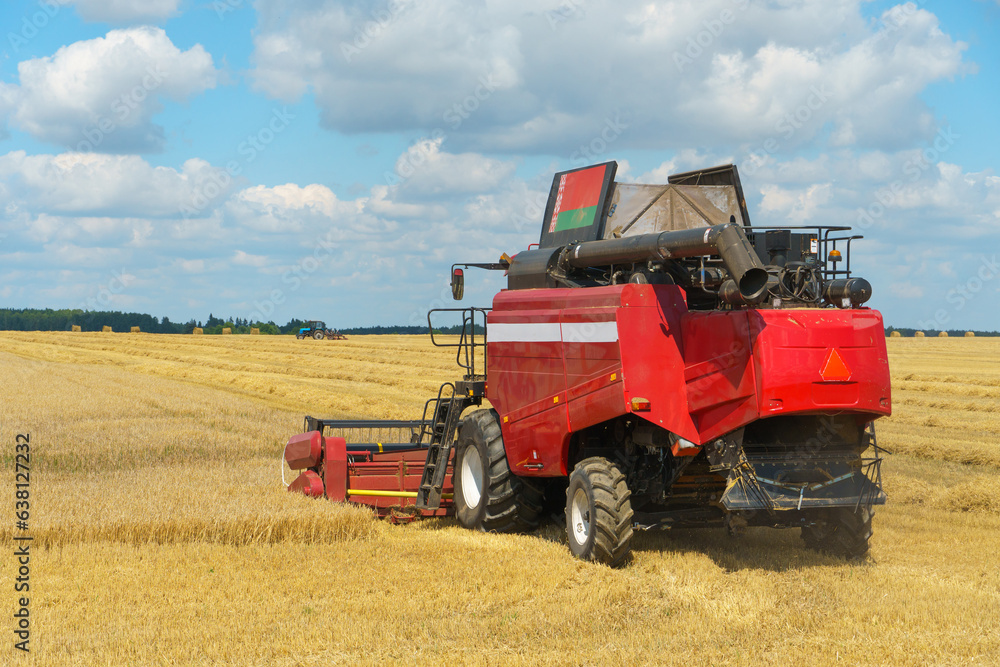 Obraz premium The combine harvester is working in the field. Agro-industrial complex, grain harvest season. Harvesting and harvesting of wheat, flour production. Grain deal.