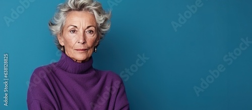 70 years old model posing for the colors of life. Aging woman standing in front a wall. Turquoise, teal, purple, grey color scheme. Grey haired baby boomer, healthy, happy, enjoying the fall of life.