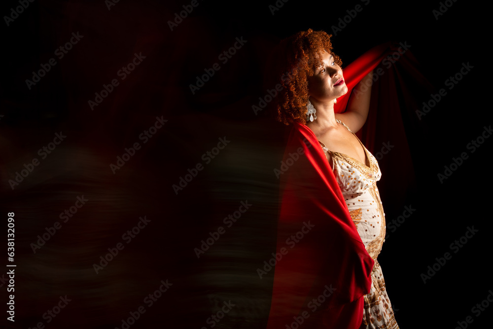 Photo taken at low speed of a beautiful woman with curly red hair with a red cloth over her body