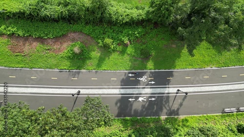 Wallpaper Mural man riding a bicycle on paved bike lane in public park shot (next to pedestrian walkway) asphalt, pavement (drone footage filmed from above) gravel, mountain, road cycling, biking, riding urban Torontodigital.ca
