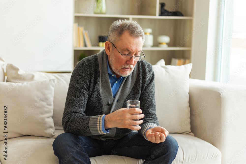 Middle aged senior man holding medical pill and glass of water. Mature old senior grandfather taking medication cure pills vitamin. Age prescription medicine healthcare therapy concept